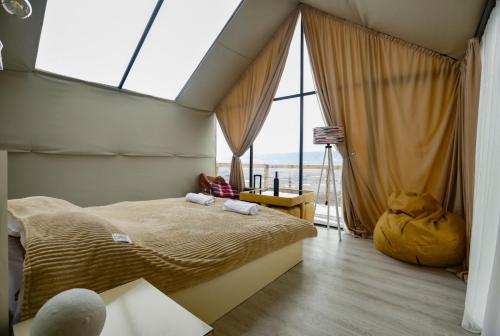 a bedroom with a bed and a large window at პანორამა სხალტბა in Mtskheta