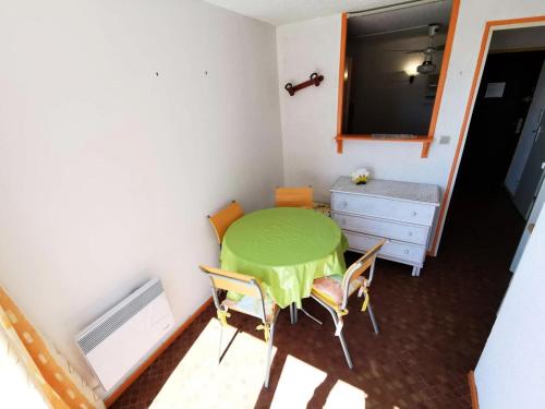 Cette petite chambre comprend une table et des chaises vertes. dans l'établissement RESIDENCE DE LA PLAGE - Studio pour 4 Personnes 94, à Port-Leucate