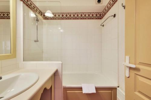 Baño blanco con lavabo y bañera en Les Issambres Lauriers - maeva Home - Studio 4 personnes Confort 77 en Les Issambres