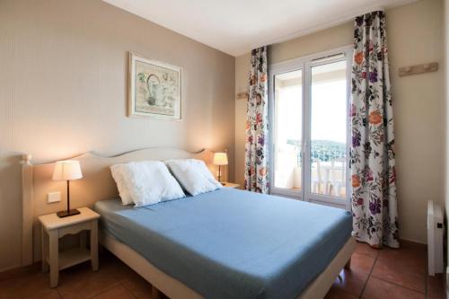 une chambre avec un lit bleu et une fenêtre dans l'établissement Les Issambres Lauriers - maeva Home - Appartement 2 pièces 5 personnes Confort MAE-1800, aux Issambres