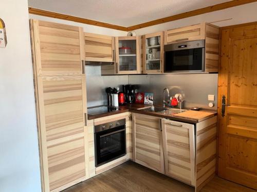 Elle comprend une petite cuisine avec des placards en bois et un évier. dans l'établissement Primevere Chalets De La Vallee D'or - 3 pièces 6 personnes 3 exposé Ouest MAE-9954, à Valloire