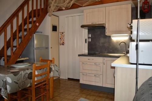 une cuisine avec des placards blancs, une table et un escalier dans l'établissement Résidence Les Fermes Marines - VILLA T1 CAB MEZZ 6 couchages PORT LEUCATE MAE-4964, à Port-Leucate