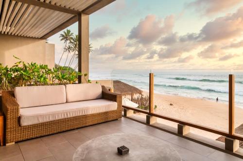 een rieten bank op een veranda met uitzicht op het strand bij The Six in Midigama East