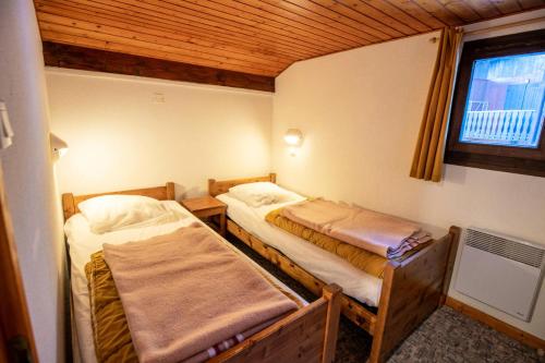 - 2 lits dans une petite chambre avec fenêtre dans l'établissement Résidence Les Epervieres - 2 Pièces pour 6 Personnes 84, à Villarodin-Bourget