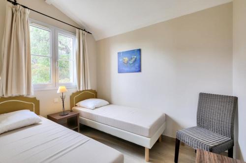 Zimmer mit 2 Betten, einem Stuhl und einem Fenster in der Unterkunft Les Bastides aux Restanques du Golfe de St Tropez - Maeva Home - Bastide spac 59 in Grimaud