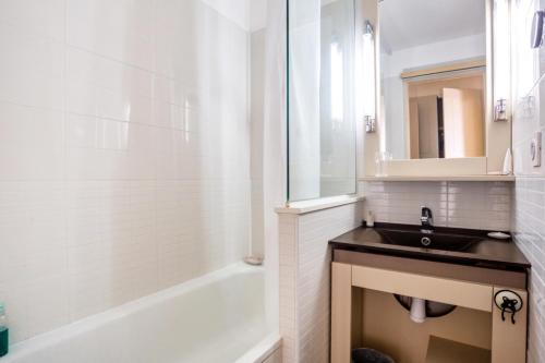 biała łazienka z umywalką i wanną w obiekcie Résidence Les Parcs de Grimaud - maeva Home - Appartement 2 pièces 4 personnes Prestige MAE-2246 w mieście Grimaud