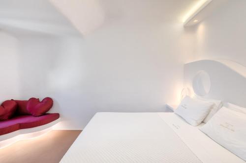 a white room with a bed and a red couch at Mykonos Dream Villas in Elia