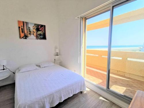 une chambre blanche avec un lit et une grande fenêtre dans l'établissement Résidence Les Nefs Des Sables - APPT T2 CAB OU MEZZ 6 couchages PORT LEUCATE. Réf: 2NEF_45K4 MAE-5304, à Port-Leucate