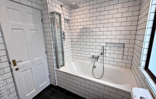 クリアンラリッチにあるLapwing chaletの白いタイル張りのバスルーム(バスタブ、シャワー付)