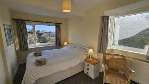 a bedroom with a bed and a window and a chair at Whitestones in Saint Mawes