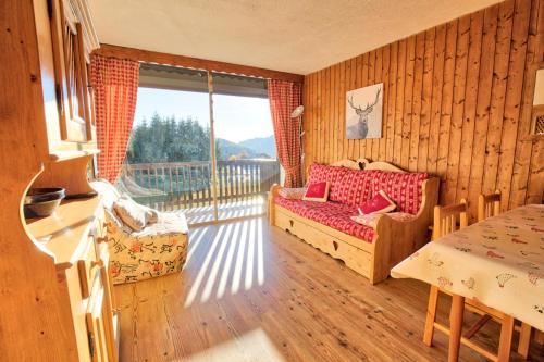 un salon avec un canapé et une grande fenêtre dans l'établissement Résidence Les Alpages - Appartement Sud avec vues montagnes, skis aux pieds MAE-2664, à Notre-Dame-de-Bellecombe