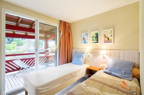 Cette chambre comprend deux lits et un balcon. dans l'établissement Village Moliets - maeva Home - Appartement 2 pièces 4 personnes Confort MAE-3029, à Moliets-et-Maa