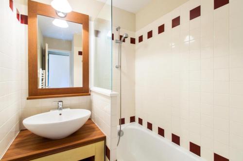 une salle de bain avec un lavabo, une baignoire et un miroir dans l'établissement Village Moliets - maeva Home - Appartement 2 pièces 4 personnes Confort MAE-3029, à Moliets-et-Maa