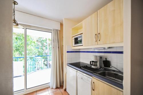 une cuisine avec un évier et une porte coulissante en verre dans l'établissement Résidence les Rivages du Parc - maeva Home - Studio 4 personnes - Sélection MAE-3056, à Menton