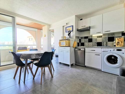 une cuisine avec une table et des chaises ainsi qu'un lave-linge dans l'établissement Résidence Terrasses De La Mediterranee 3 - APPT T2 CAB OU MEZZ 4 couchages PORT LEUCATE MAE-5434, à Port-Leucate