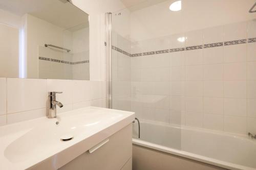 Baño blanco con lavabo y bañera en Résidence Port Guillaume - maeva Home - Studio 2 personnes Sélection MAE-3802, en Dives-sur-Mer