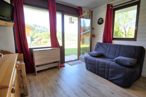 ein Wohnzimmer mit einem Sofa und großen Fenstern in der Unterkunft Résidence Le Champs Sous Jerome - Studio de charme MAE-2754 in Notre-Dame-de-Bellecombe