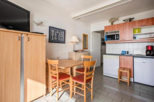 une cuisine avec une table et des chaises en bois ainsi qu'une cuisine avec un comptoir dans l'établissement Résidence Les Océanes - maeva Home - Studio 5 personnes Confort - vue mer MAE-3803, à Pornichet