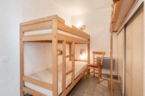 Cette chambre dispose de lits superposés, d'un bureau et d'une chaise. dans l'établissement Résidence Les Océanes - maeva Home - Studio 5 personnes Confort - vue mer MAE-3803, à Pornichet