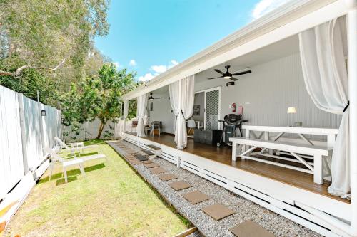 a living area with a patio and a house at Private Outdoor Spa, Fire Pit, Cinema Room - THE COTTAGE COOLUM BEACH in Coolum Beach