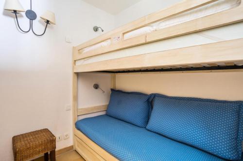 Ce lit superposé se trouve dans une petite chambre dotée de draps bleus. dans l'établissement Les Appartements aux Restanques du Golfe de St Tropez - maeva Home - Appartement 4 personnes avec terrasse vue mer - Sélection MAE-4506, à Grimaud