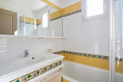 La salle de bains est pourvue d'un lavabo blanc et d'une baignoire. dans l'établissement Les Appartements aux Restanques du Golfe de St Tropez - maeva Home - Appartement 4 personnes avec terrasse vue mer - Sélection MAE-4506, à Grimaud