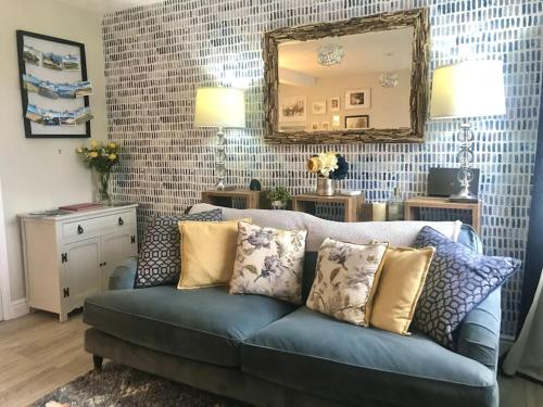 a living room with a blue couch and a mirror at Charming Coastal Getaway - Pembroke in Pembrokeshire