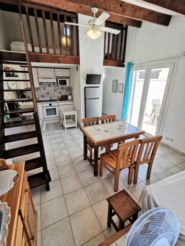 une cuisine avec une table et des chaises dans une pièce dans l'établissement Résidence Les Leucatines 1 - VILLA T2 MEZZANINE 6 couchages PORT LEUCATE MAE-5524, à Port-Leucate