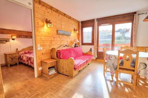 a bedroom with wooden walls and a bed and a table at Les Chalets Des Evettes - 3 Pièces pour 6 Personnes 64 in Notre-Dame-de-Bellecombe