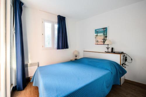 une chambre avec un lit bleu et une fenêtre dans l'établissement Résidence La Pinède - maeva Home - Appartement 2 pièces 6 personnes Sélection - WIFI inclus MAE-4732, à Hyères