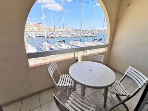 une table et des chaises devant une fenêtre avec des bateaux dans l'établissement Résidence Terrasses De La Mediterranee 1 - 2 Pièces 4 couchages PORT LEUCATE MAE-5654, à Port-Leucate
