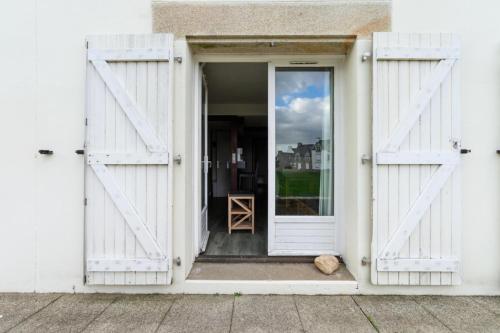 une porte ouverte d'un bâtiment blanc avec un chat assis à l'intérieur dans l'établissement Résidence Port du Crouesty - maeva Home - Appartement 2 pièces 5 personnes Confort MAE-4763, à Arzon