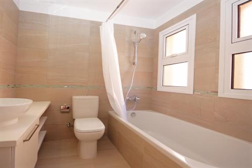 a bathroom with a toilet and a tub and a sink at Resitour - Aphrodite Gardens in Paphos City