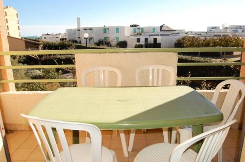 a green table and white chairs on a balcony at Résidence BELLE PLAGE - 2 Pièces pour 4 Personnes 44 in Port Leucate