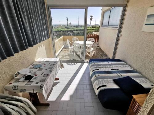 Cette chambre comprend deux lits et un balcon avec une table. dans l'établissement Résidence LES NEFS DES SABLES - Studio pour 4 Personnes 74, à Port-Leucate