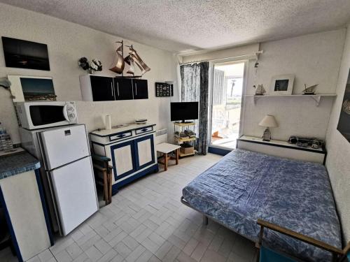 Cette chambre dispose d'une cuisine avec un lit et un réfrigérateur. dans l'établissement Résidence LES NEFS DES SABLES - Studio pour 4 Personnes 74, à Port-Leucate