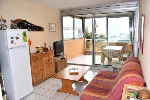 - un salon avec un canapé et un réfrigérateur dans l'établissement Résidence Le Neptune - 2 Pièces pour 5 Personnes 64, à Port-Leucate