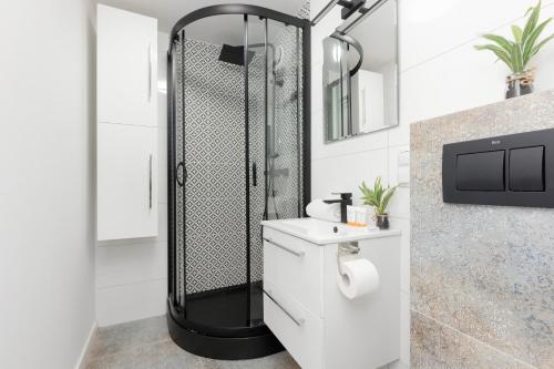 bagno con doccia e lavandino bianco di Cozy Studio Batorego by Rent like home a Varsavia