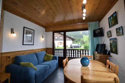 a living room with a blue couch and a wooden table at Résidence L'edelweiss-planay - Studio pour 4 Personnes 84 in Notre-Dame-de-Bellecombe