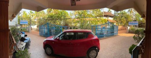 a small red car parked in front of a gate at hello beach view resorts in Varkala