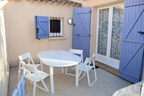une table et des chaises sur une terrasse avec portes bleues dans l'établissement Résidence Les Maisons Du Soleil - VILLA T2 MEZZANINE 4 couchages PORT LEUCATE MAE-5914, à Port-Leucate