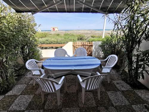une table avec quatre chaises et une couverture bleue sur une terrasse dans l'établissement Résidence Les Captivantes - Villa trois pièces mezzanine face à la mer avec garage à Port Leucate. Réf: 1CAPT_H3 MAE-5964, à Port-Leucate