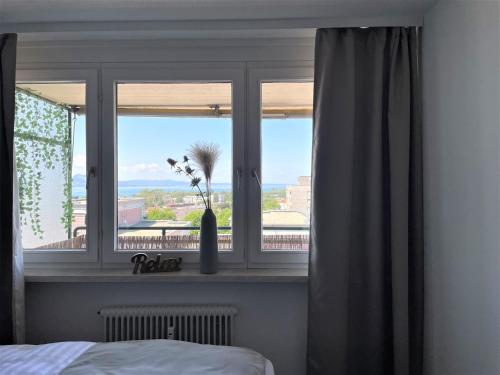 Un dormitorio con una ventana con un jarrón con flores. en Apartment mit Terassee & Aussicht auf See und Berge en Lochau