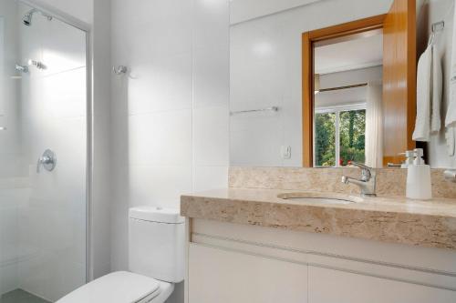 a bathroom with a toilet and a sink and a mirror at Casa de Pedra 2 Suítes e Piscina by Achei Gramado in Gramado