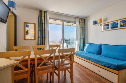 un salon avec un canapé bleu, une table et des chaises dans l'établissement Résidence Les Océanes - maeva Home - Appartement 2 pièces 6 personnes Confort - vue mer MAE-6393, à Pornichet