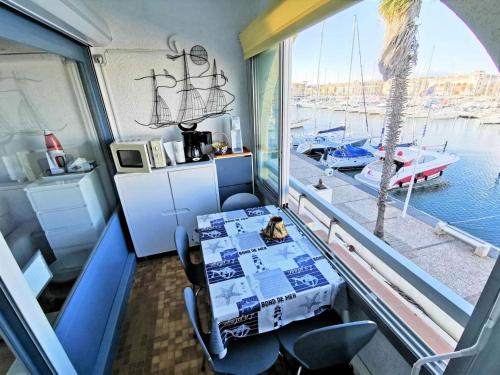 a dining room with a table and a large window at Résidence LES TERRASSES DU PORT - 2 Pièces pour 4 Personnes 04 in Port Leucate