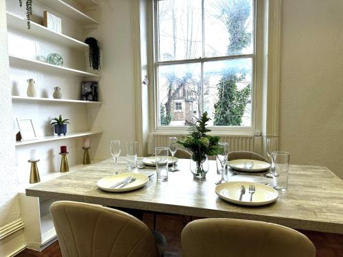 a dining room table with chairs and a large window at Captivating 2-Bed Flat in Maida Vale near Abbey Road in London