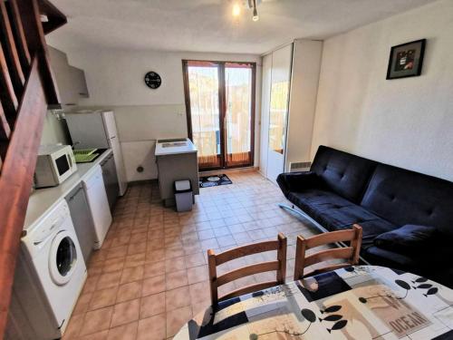 uma sala de estar com um sofá preto e uma cozinha em Résidence MAISONS DE LA PLAGE - Maisons & Villas pour 6 Personnes 074 em Port Leucate
