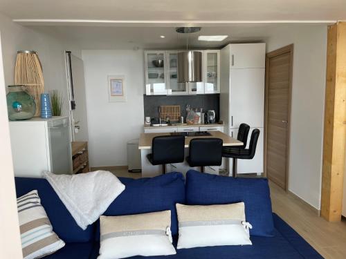 un salon avec un canapé bleu et une cuisine dans l'établissement Magnifique vue mer dans une résidence avec piscine, à Théoule-sur-Mer