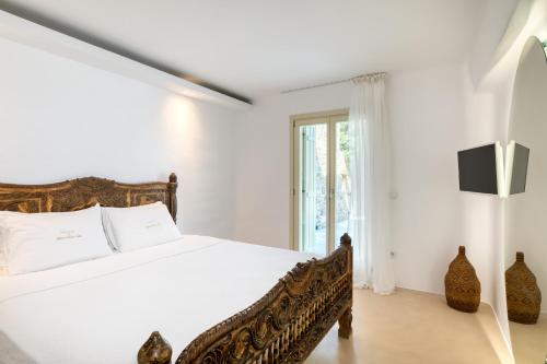 a white bedroom with a bed and a window at Mykonos Dream Villas in Elia